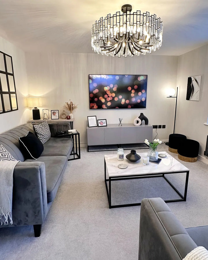 Modern living room with gray sofa, coffee table, and chandelier.