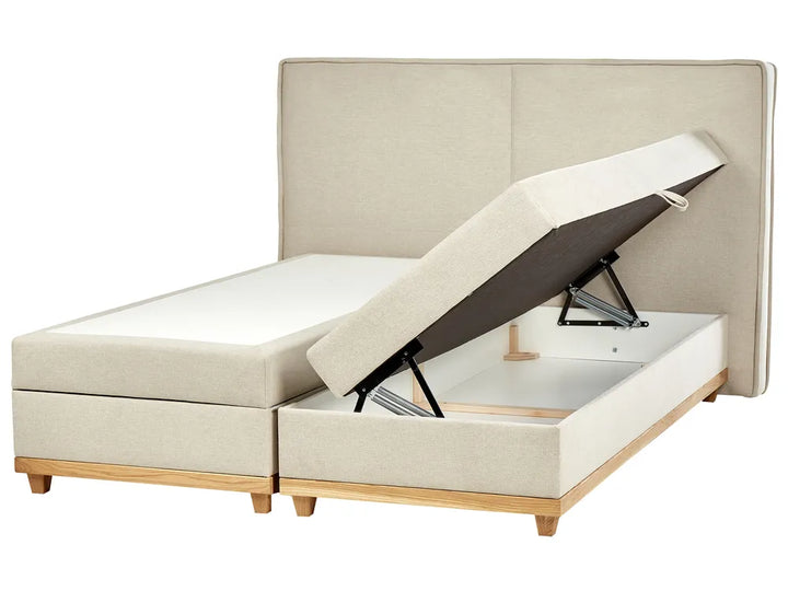 Beige upholstered bed with storage compartment on a white background