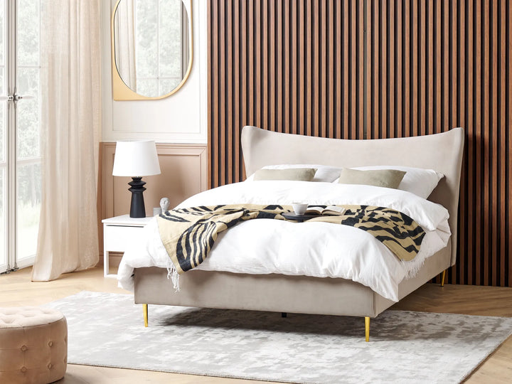 Beige bed with white bedding and a patterned throw in a modern bedroom.