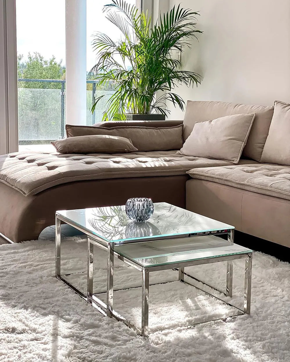 Modern living room with a beige sectional sofa and glass coffee table.