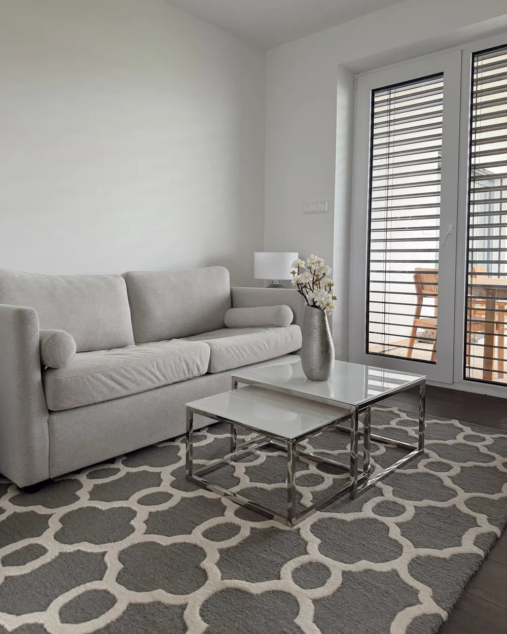 Modern living room with a gray sofa, coffee table, and patterned rug.