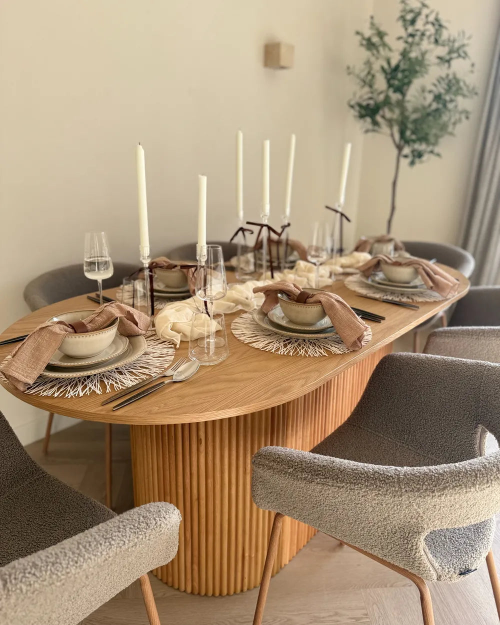 Dining table set with plates, glasses, and candles in a cozy room.