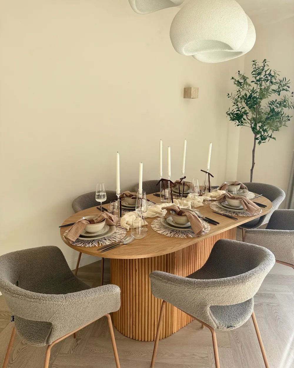 Dining room with a wooden table set for a meal, surrounded by gray chairs.