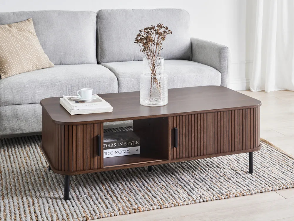 Brown coffee table with books and a vase in a living room setting