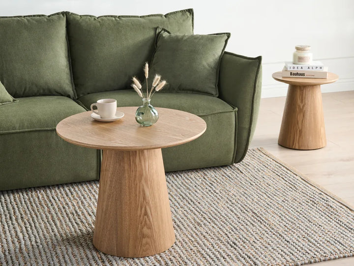 Green sofa with a wooden side table and a small plant in a living room setting.