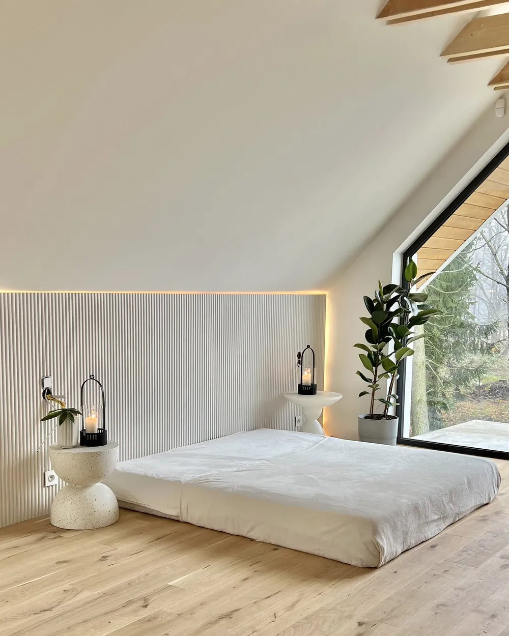 Modern bedroom with a large window, bed, and decorative elements.