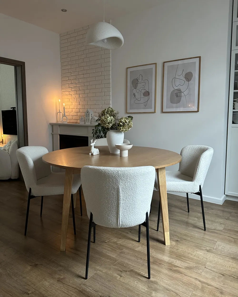 Dining area with a round wooden table and white chairs in a modern living room.