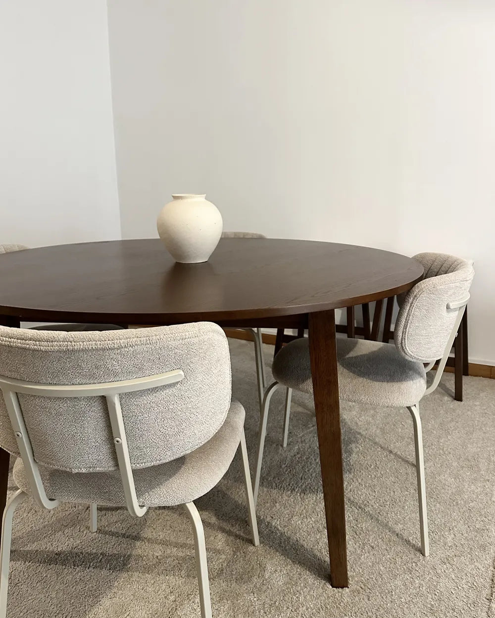 Dining table with chairs in a room with a plain wall.