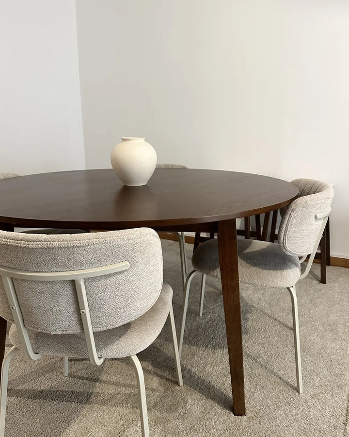 Dining table with chairs in a room with a plain wall.