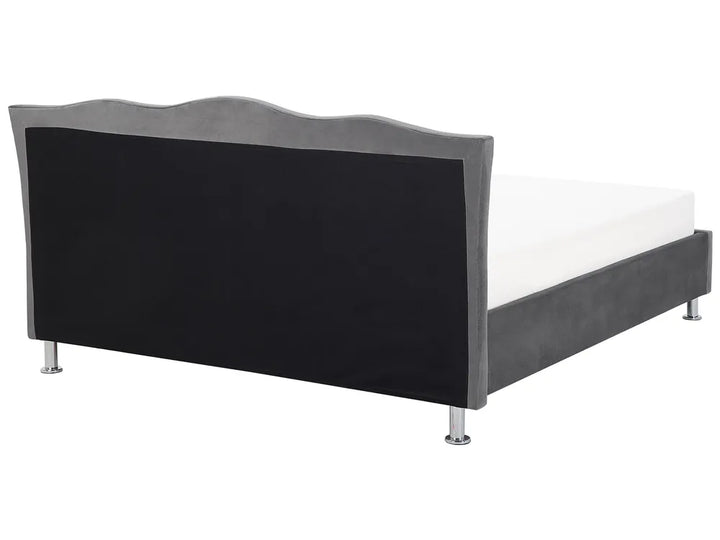 Bed with black upholstered headboard and white mattress on a white background