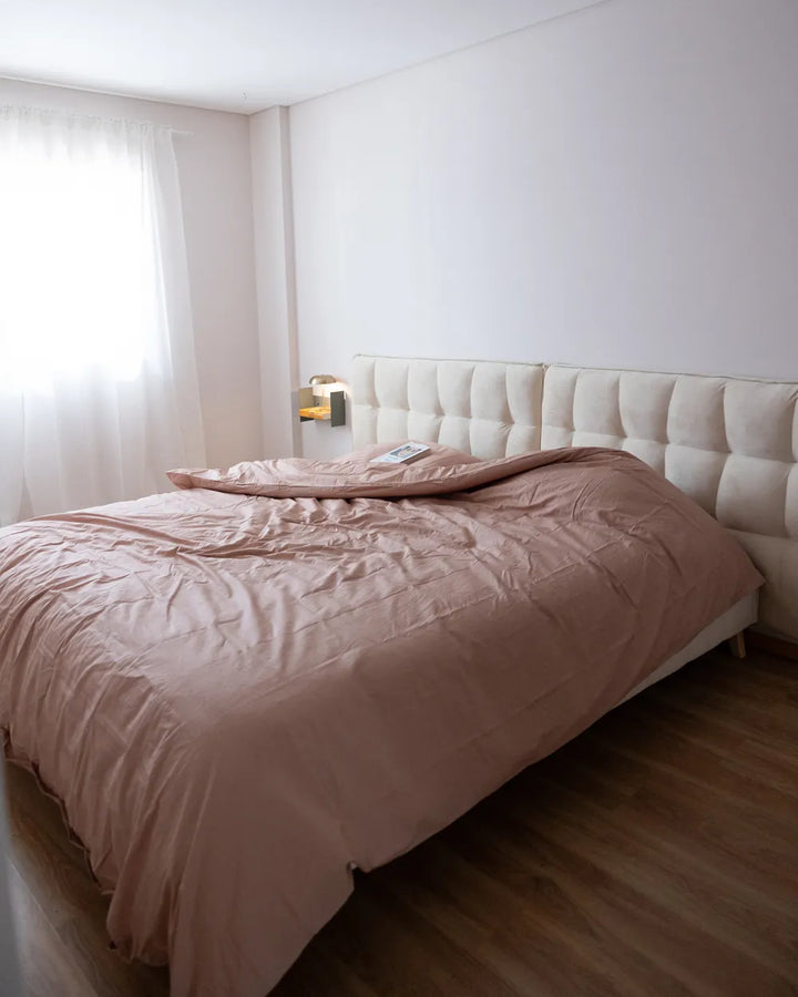 Bedroom with a bed featuring a pink comforter and white headboard.