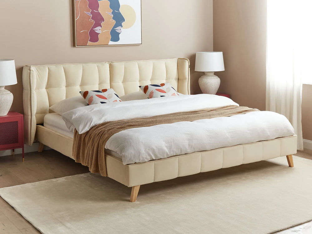 Beige upholstered bed with white bedding in a bedroom setting.
