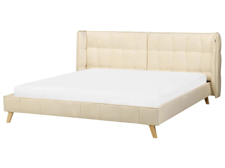 Beige upholstered bed with white mattress on a white background