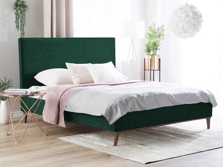 Green bed with white bedding in a bright bedroom
