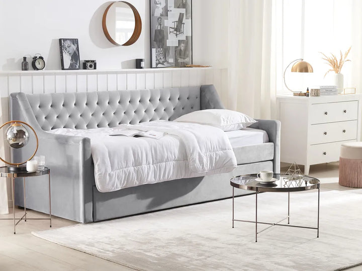 Gray upholstered bed in a modern bedroom setting with white walls and decor.