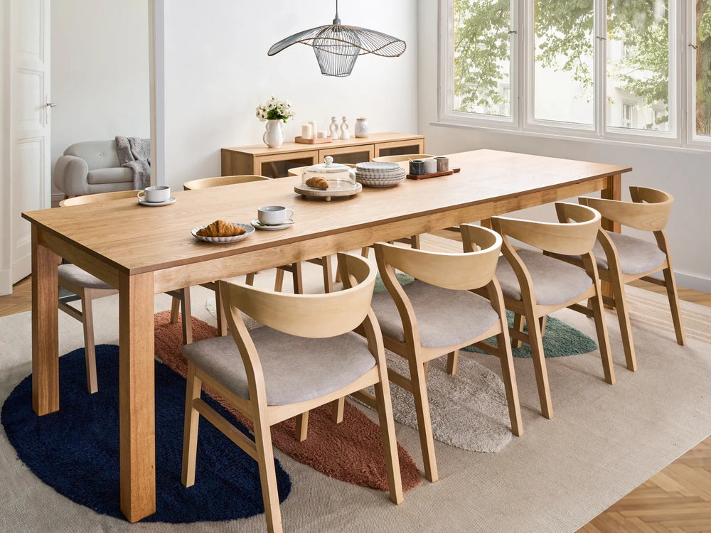 Dining room with a long wooden table and chairs in a modern home setting.