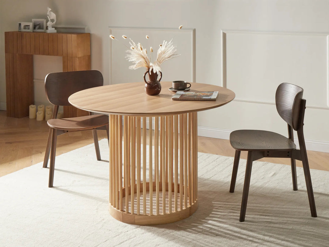 Round wooden dining table with chairs in a room setting