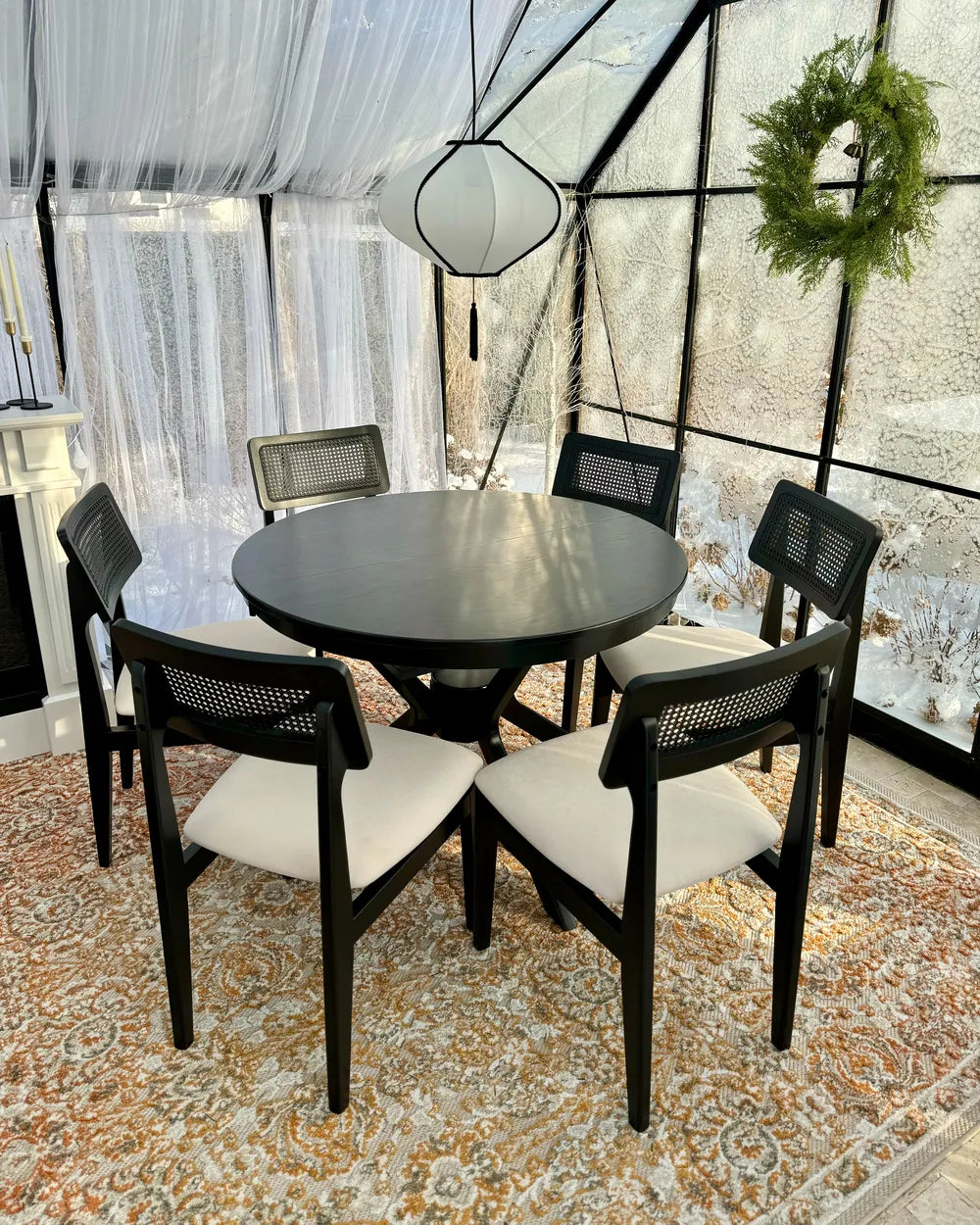 Dining area with a round black table and four chairs on a patterned rug.