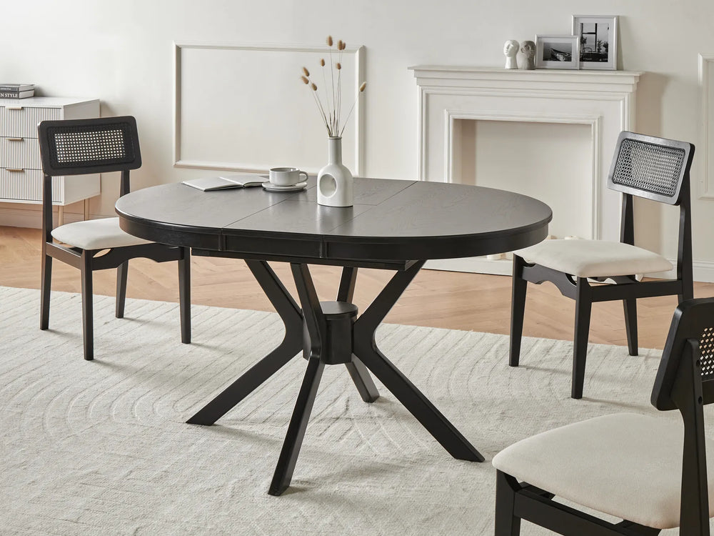 Round dark wood dining table with four chairs in a room with a fireplace and white walls.