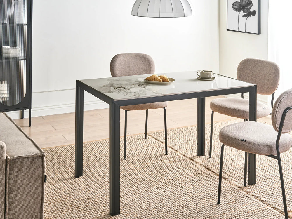 Dining area with a table and chairs in a room with a rug and lamp.