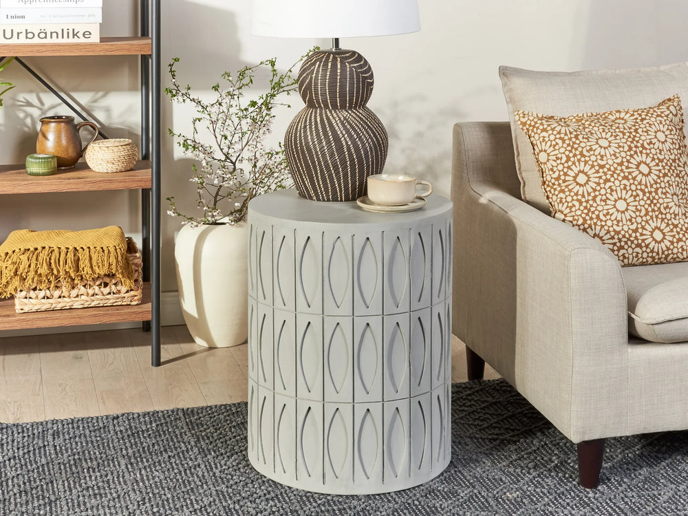 Decorative side table in a living room setting with a lamp and cup.