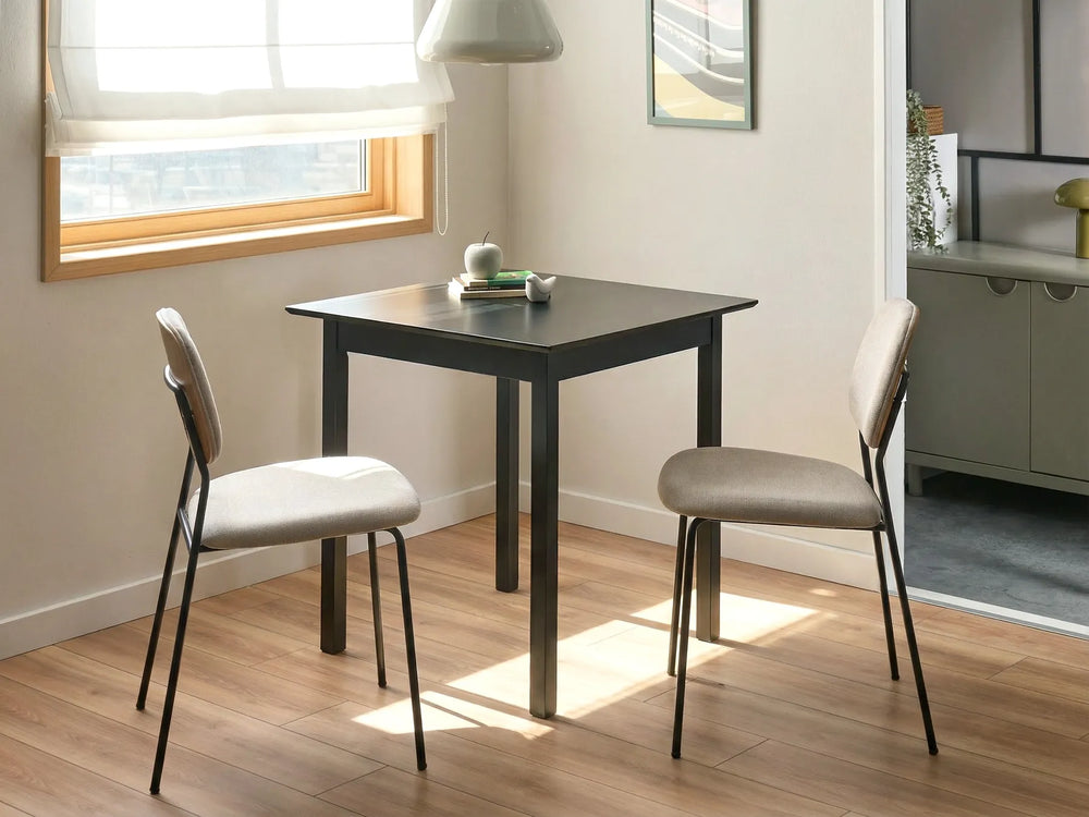 Small black dining table with two gray chairs in a room with a window.