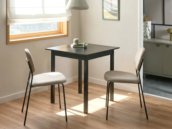 Small black dining table with two gray chairs in a room with a window.