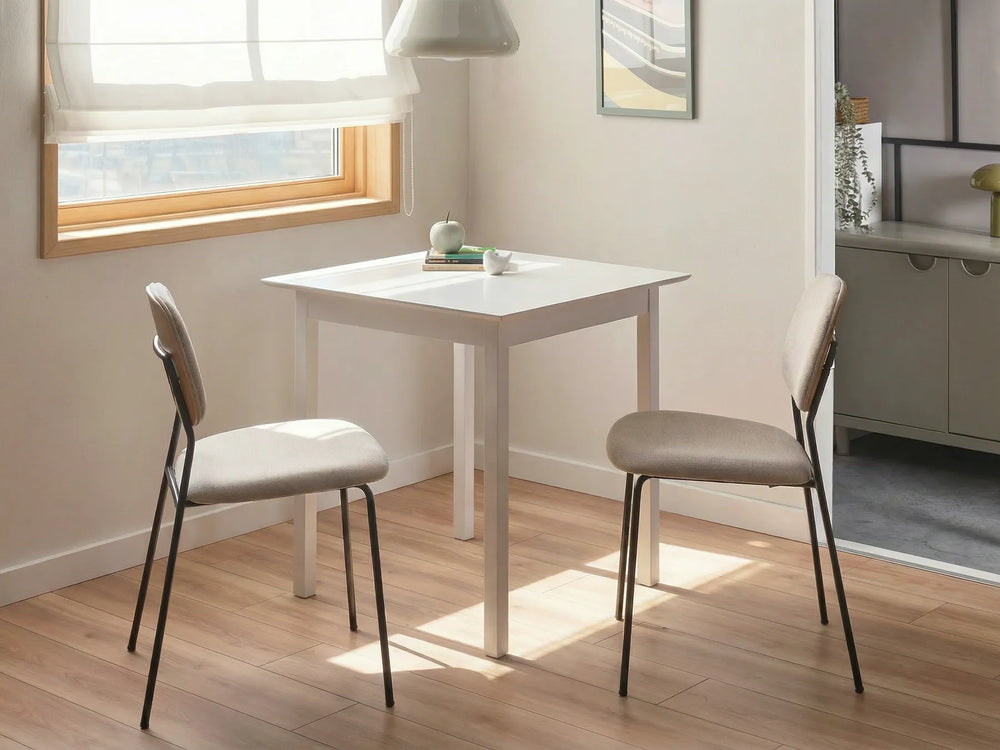 White dining table with two chairs in a room with a window and a dresser.