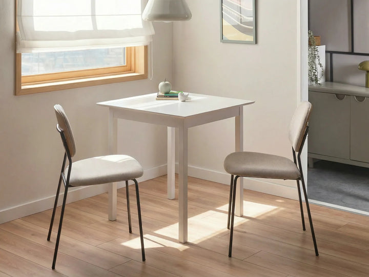 White dining table with two chairs in a room with a window and a dresser.