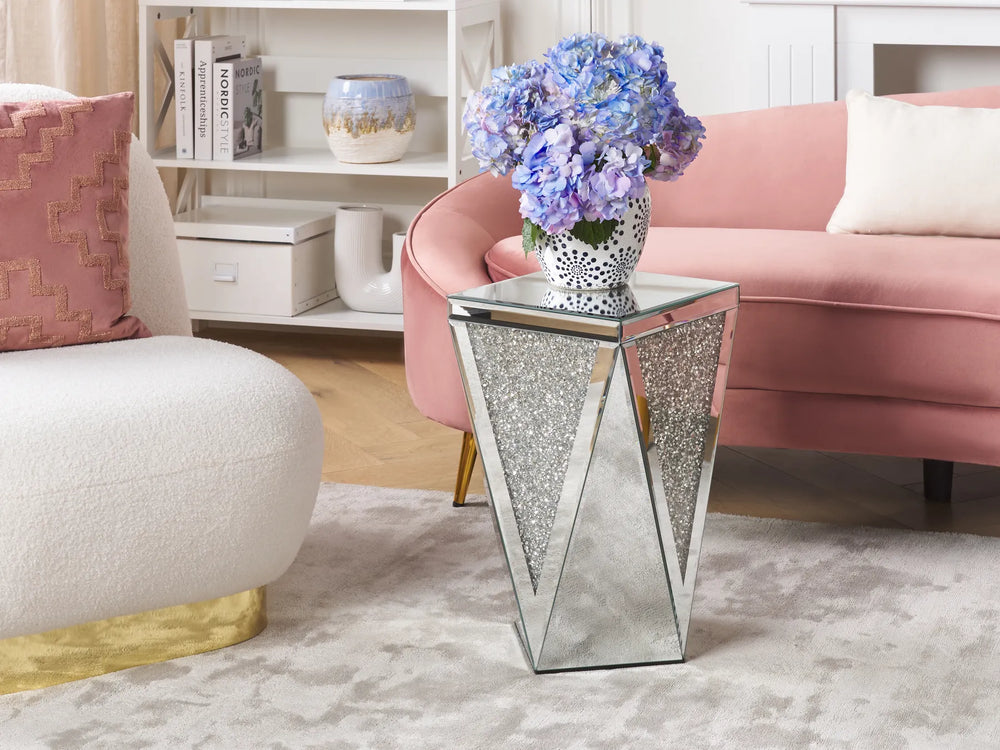 Decorative side table with a vase of blue flowers in a living room setting.