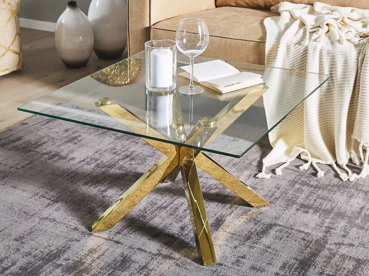 Glass coffee table with gold legs in a living room setting