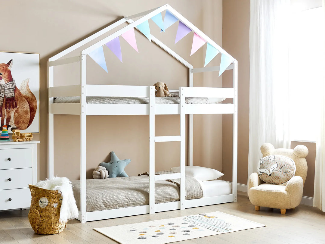 Children's room with a white house-shaped bunk bed, colorful flags, and decorative items.