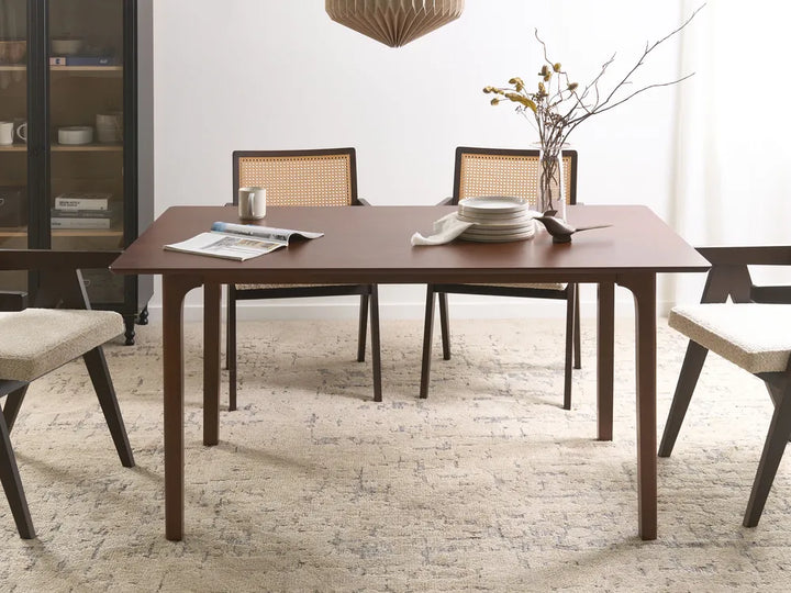 Dining room with a wooden table and chairs on a textured rug.