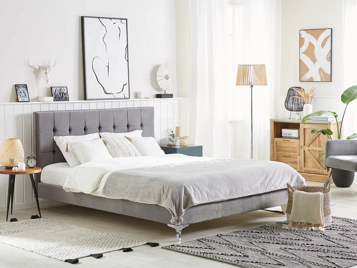 Modern bedroom with a gray upholstered bed, white bedding, and decorative items.