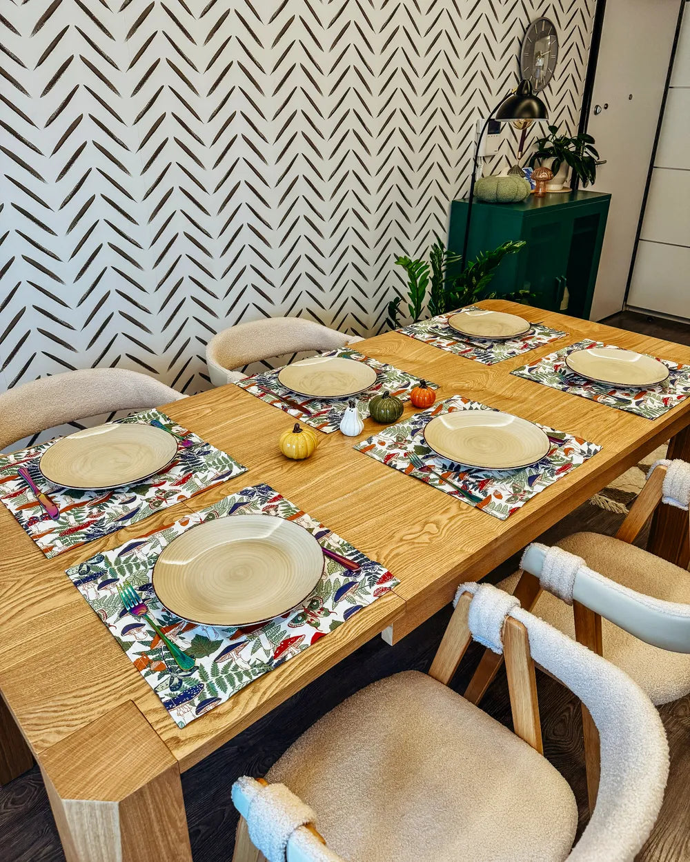 Dining table set with plates, napkins, and decorative items against a patterned wall.