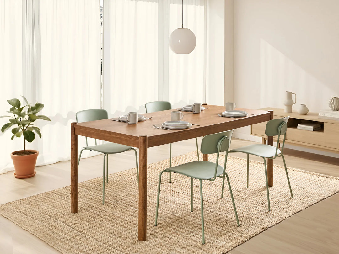 Dining area with wooden table and green chairs in a bright room.