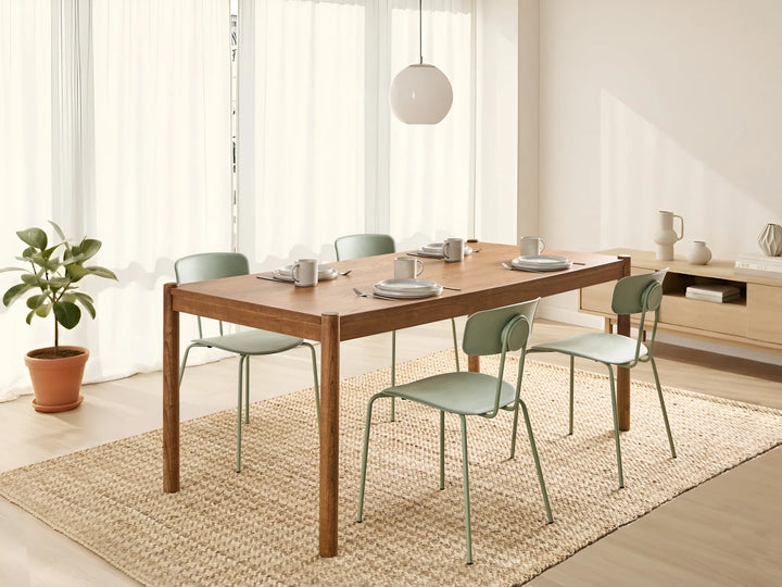 Dining area with wooden table and green chairs in a bright room.