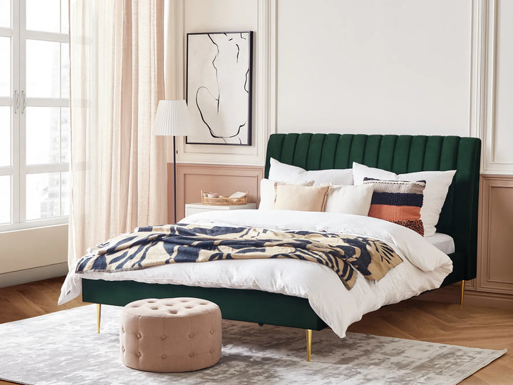 Green upholstered bed with white bedding and patterned throw in a bedroom setting.