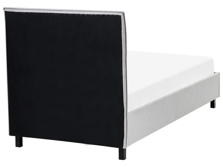 Bed with black upholstered headboard and white mattress on a white background