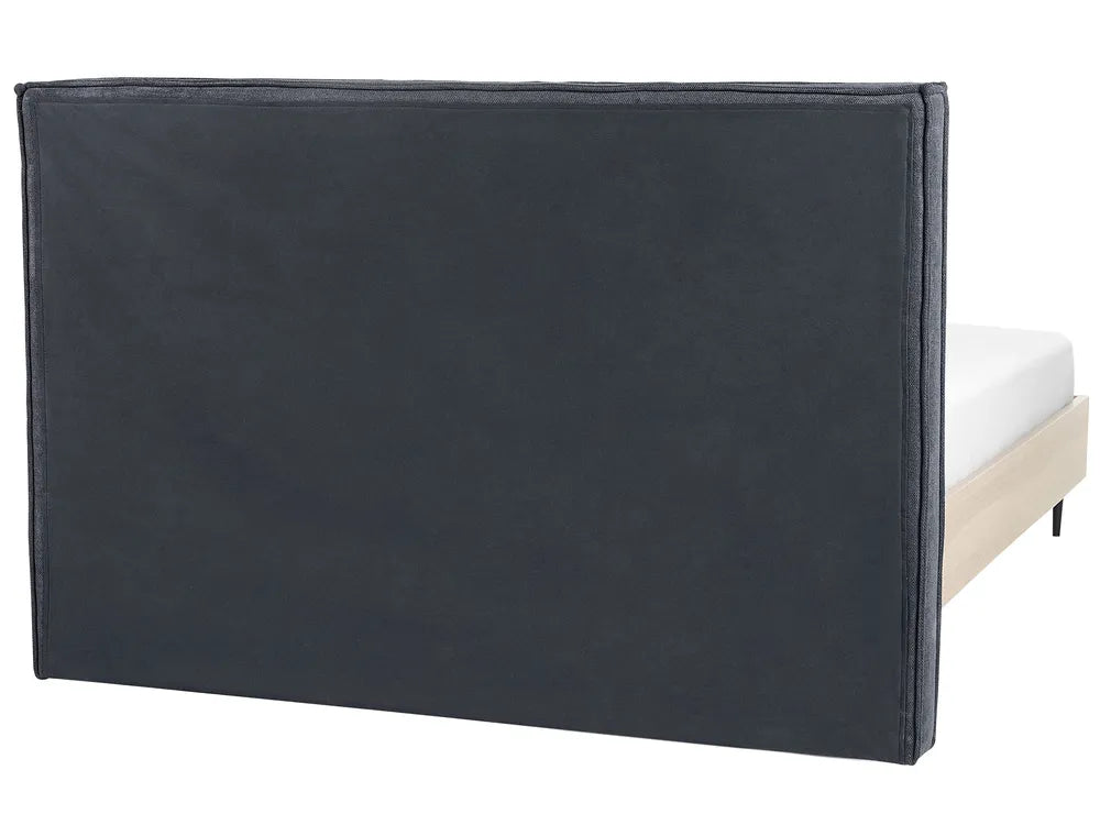 Black upholstered headboard on a bed with white mattress