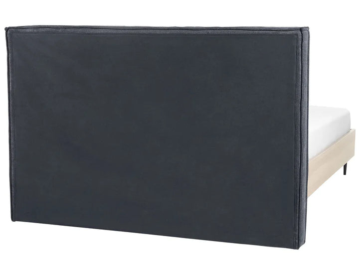 Black upholstered headboard on a bed with white mattress