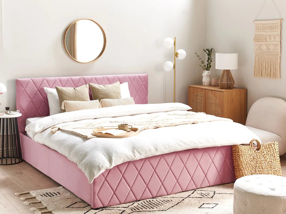 Pink bed in a bedroom with white walls and decorative items.