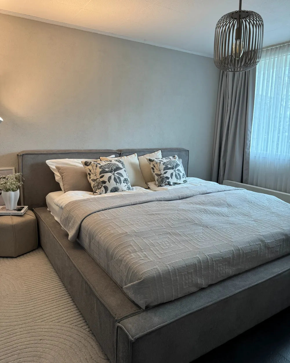 Neatly made bed with decorative pillows in a modern bedroom setting.