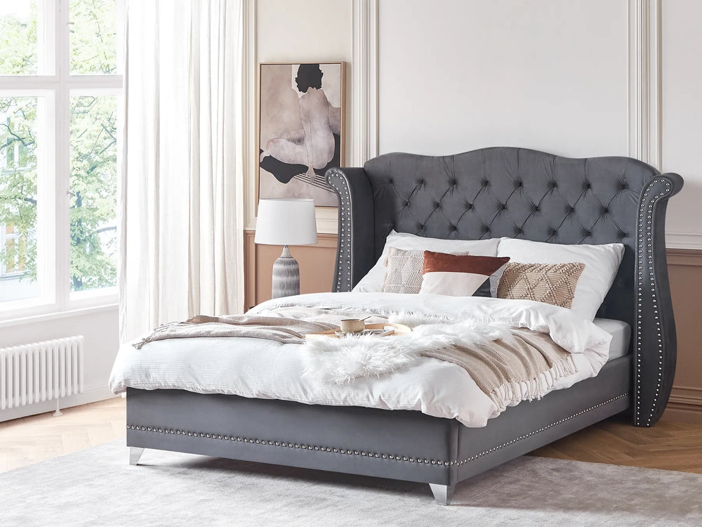Gray upholstered bed with white bedding in a bright bedroom