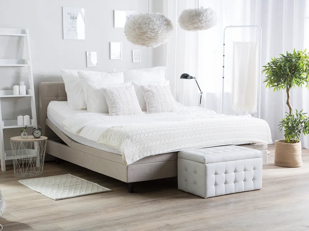 Modern bedroom with a bed, ottoman, and decorative elements.