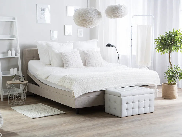 Modern bedroom with a bed, ottoman, and decorative elements.