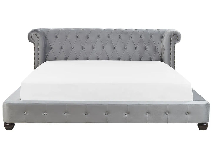 Gray tufted bed with white mattress on a white background