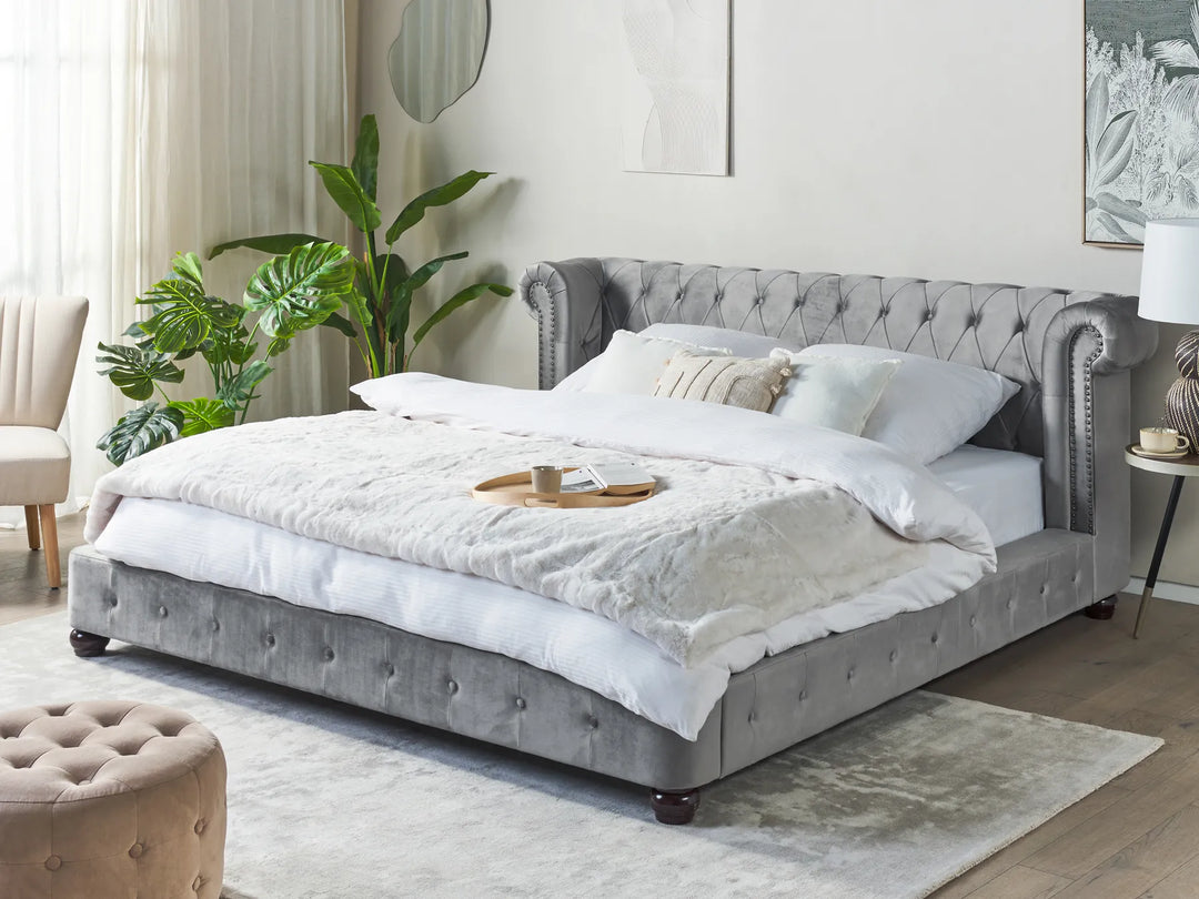 Gray tufted bed with white bedding in a bedroom setting