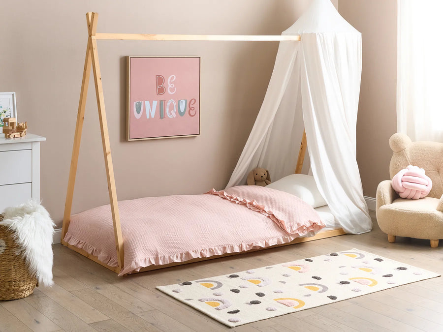 Children's room with a teepee bed, pink bedding, and decorative elements.