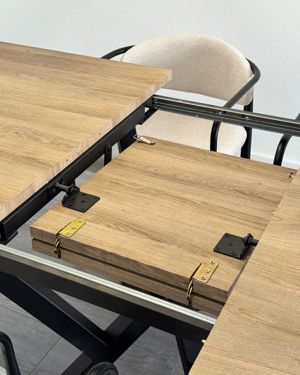 Wooden folding table with metal frame and chair in the background